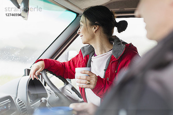 Frau mit Kaffee am Steuer eines Wohnmobils