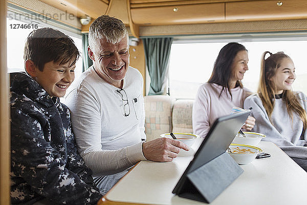 Familie entspannt sich  frühstückt und benutzt ein digitales Tablet im Wohnmobil