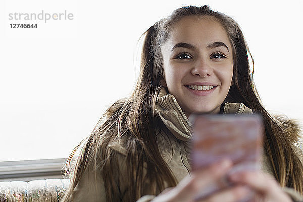 Porträt lächelnd  selbstbewusstes Teenager-Mädchen  das eine SMS mit einem Smartphone schreibt