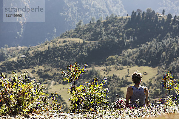 Weibliche Wanderin ruht sich aus und genießt die sonnige Aussicht  Supi Bageshwar  Uttarakhand  Indische Himalaya-Ausläufer