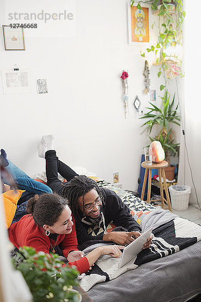 Junges Paar  das sich auf dem Bett mit einem digitalen Tablet entspannt