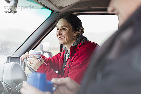 Lächelnde Frau trinkt Kaffee und fährt Wohnmobil