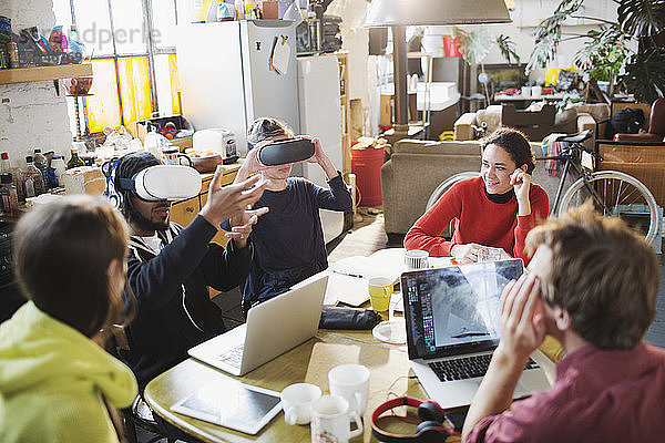 Junge Studentenfreunde beim Lernen mit einer Virtual-Reality-Simulatorbrille am Küchentisch in einer Wohnung