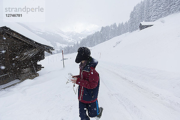 Jugendlicher beim Spaziergang vor einer verschneiten Berghütte  Forclaz  Schweiz