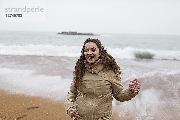 Porträt glückliches  sorgloses Teenager-Mädchen am verschneiten Winterstrand
