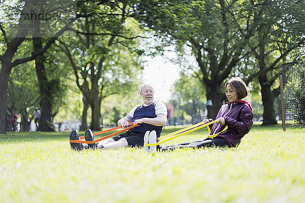 Active senior couple exercising  using resistance bands in park