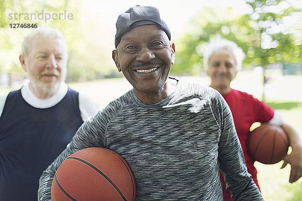 Portrait confident  smiling active senior men friends with basketballs in park