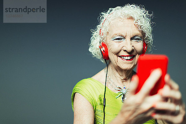 Carefree senior woman with headphones and mp3 player listening to music