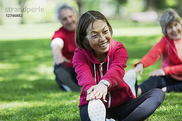 Happy active senior woman stretching leg in park