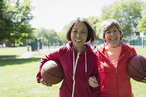 Portrait happy  active senior women friends playing basketball in sunny park