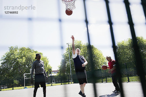 Active senior men playing basketball in sunny park