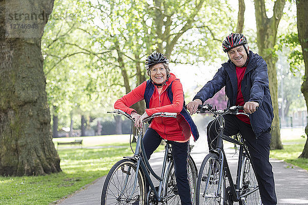 Portrait smiling  confident active senior couple riding bikes in park