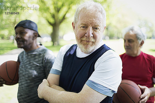 Portrait confident active senior man playing basketball with friends