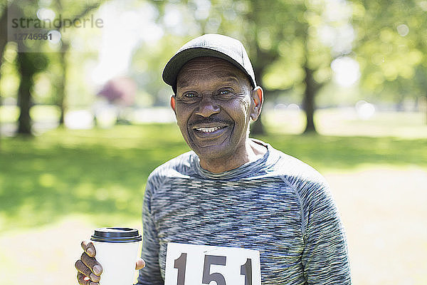 Portrait smiling  confident active senior man drinking coffee before sports race in park