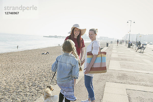 Lesbian couple with daughter and dog on sunny beach boardwalk