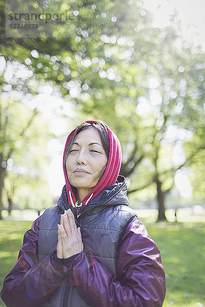 Serene active senior woman meditating in sunny park