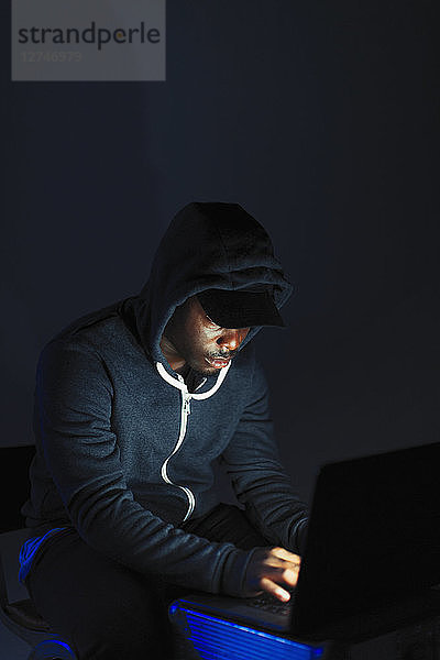 Teenage boy in hoody sitting at laptop