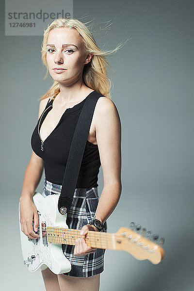 Portrait confident  cool young woman playing electric guitar