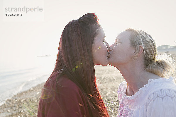 Affectionate lesbian couple kissing on sunny beach