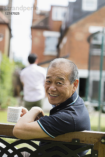 Portrait smiling senior man drinking tea in yard