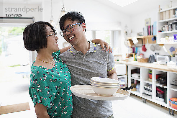Affectionate couple hugging  doing dishes in kitchen