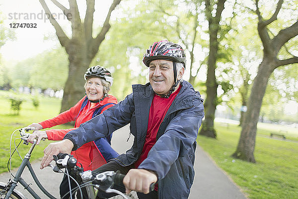 Active senior couple riding bikes in park