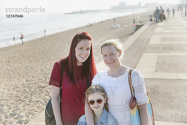 Portrait smiling lesbian couple and daughter on sunny beach boardwalk