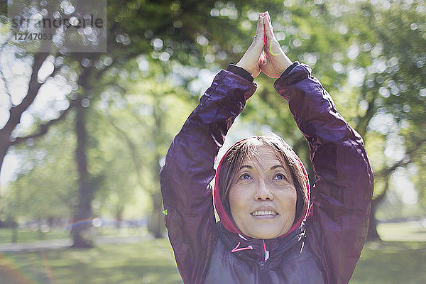 Active senior woman exercising  practicing yoga in park