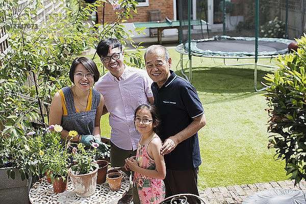 Portrait smiling multi-generation family gardening  potting flowers in sunny yard