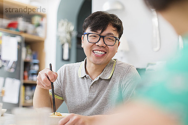 Happy man eating noodles with chopsticks