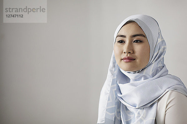 Portrait serene young woman in blue silk hijab looking away