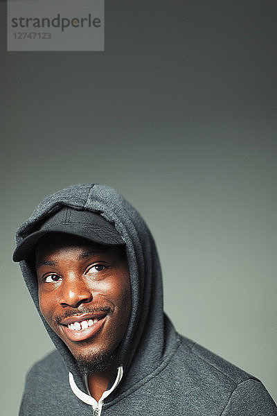 Portrait confident  smiling teenage boy in hoody looking up