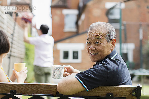 Portrait smiling senior man drinking tea with family in yard