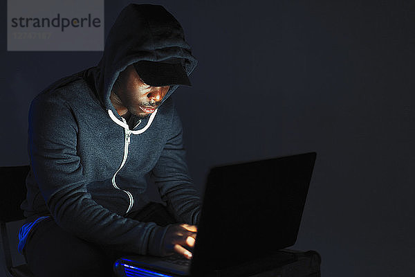 Teenage boy in hoody leaning over laptop