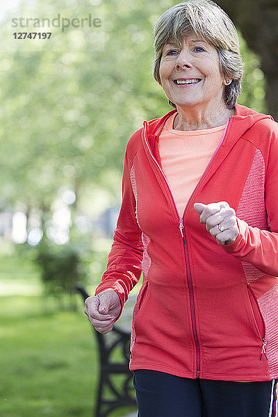 Smiling active senior woman running in park