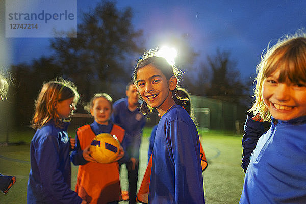 Porträt lächelnde Mädchen-Fußballmannschaft auf dem Feld bei Nacht