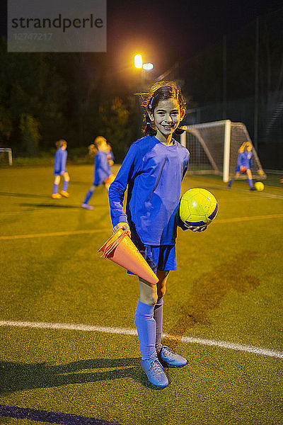 Porträt selbstbewusstes Mädchen Fußballspieler auf Feld bei Nacht