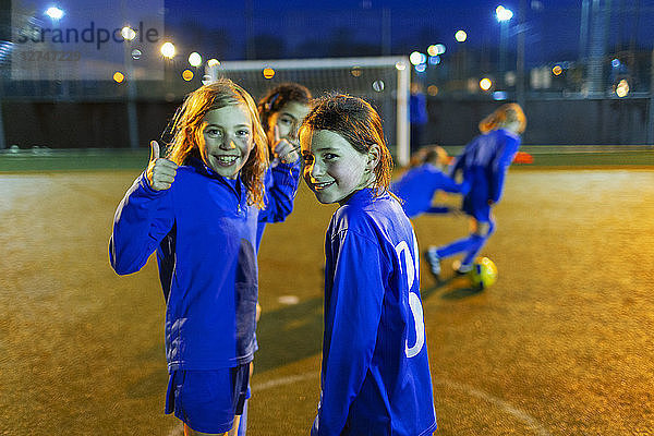 Porträt selbstbewusstes Mädchen  das Fußball spielt und den Daumen nach oben streckt