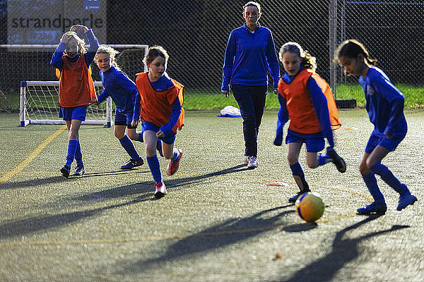 Fußballtrainer beobachtet Mädchen beim Training auf dem Feld