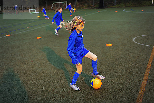 Mädchen beim Üben von Fußballübungen auf einem Feld bei Nacht