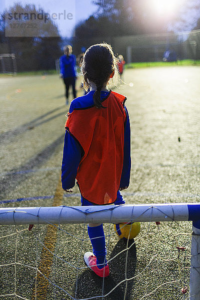 Mädchen spielt Fußball auf einem Feld bei Nacht