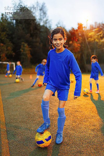 Porträt selbstbewusstes Mädchen übt Fußball auf dem Feld