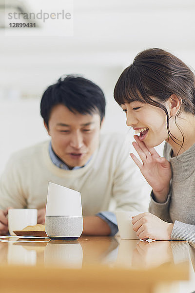Japanisches Paar in der Küche mit Smart-Home-Assistent