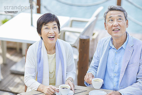 Japanisches Seniorenpaar bei einem Drink am Meer