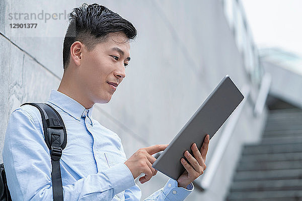 Junger Geschäftsmann benutzt digitales Tablet auf einer Stadttreppe  Shanghai  China