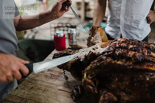 Mann schneidet Schweinebraten auf Tisch  geschnitten