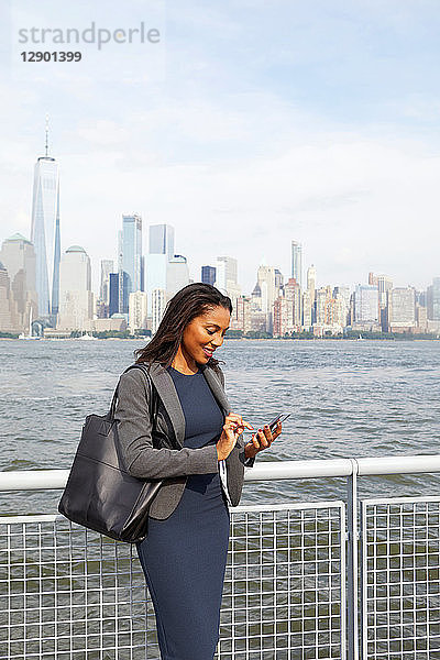 Geschäftsfrau telefoniert mit ihrem Handy  im Hintergrund die Skyline von New York City