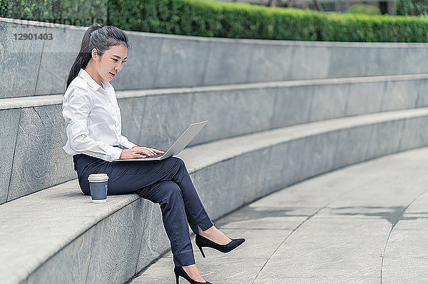 Junge Geschäftsfrau tippt am Laptop auf einem Stadtsitz  Shanghai  China