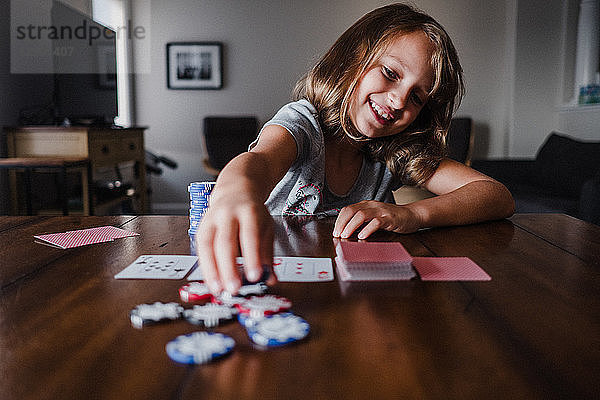 Mädchen spielen Karten am Tisch  platzieren Glücksspielchips