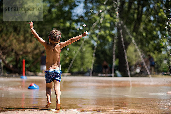 Junge spielt am Springbrunnen im Park